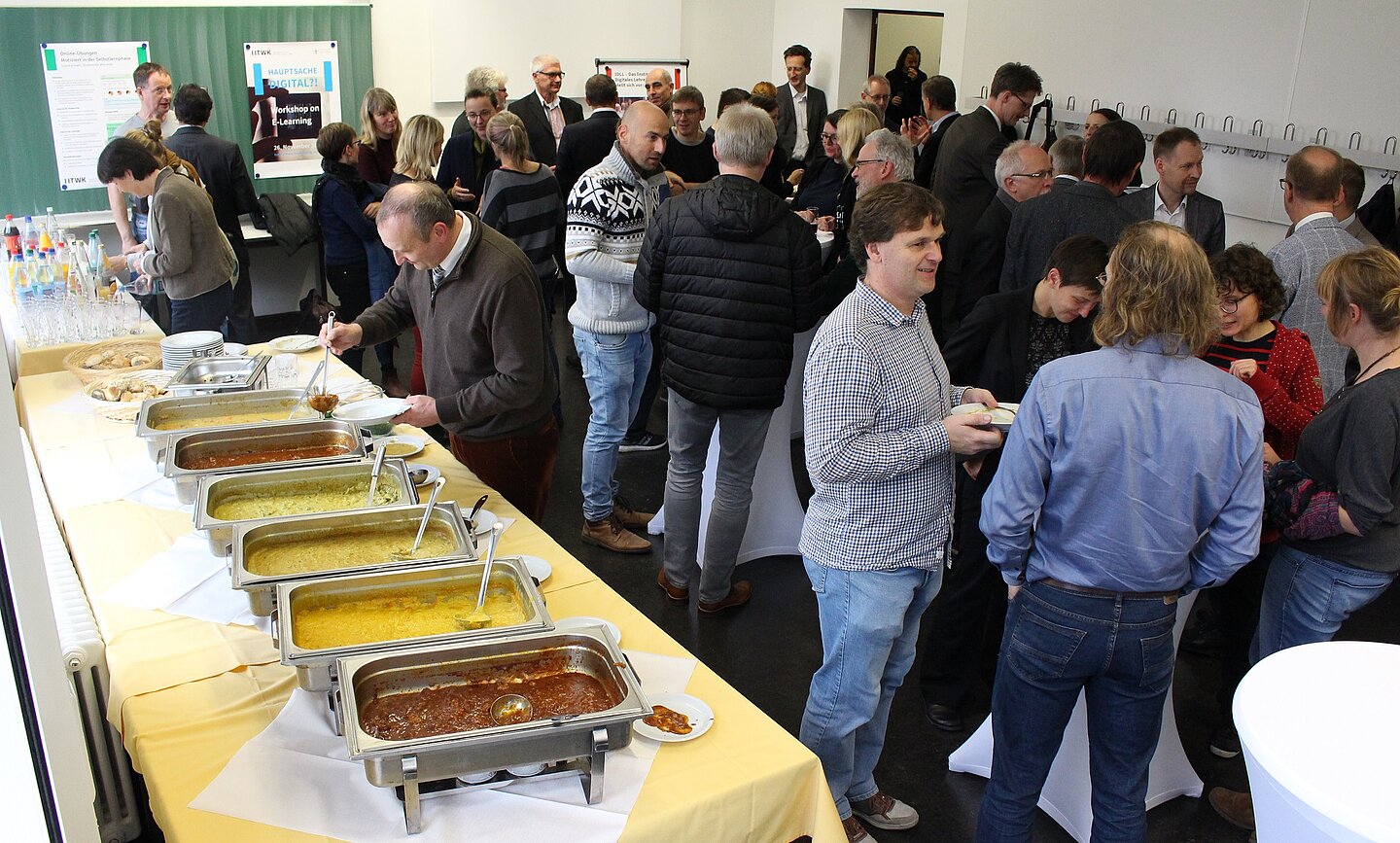 Rege Beteiligung am „Lunch and Listen plus“ Viele Personen vertieft in Gesprächen neben einem Suppenbuffet.