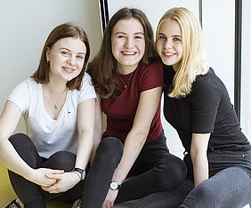 Drei junge Mädchen sitzen auf dem Boden.
