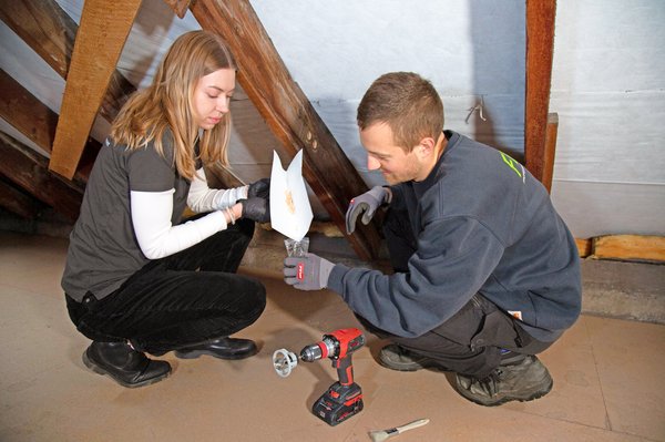 Zwei Forschende sammeln in Dachstuhl Holzproben in Behälter