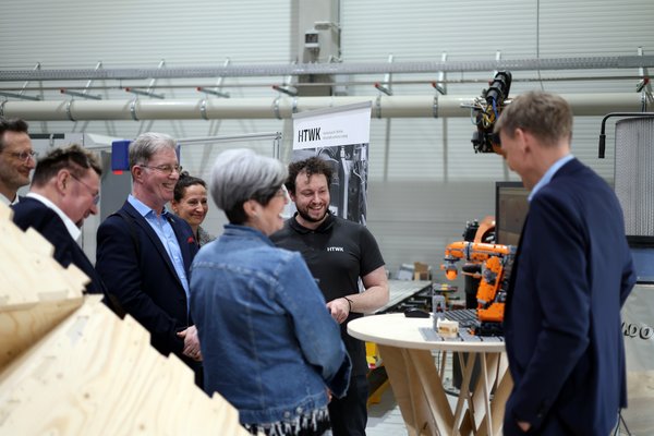 Führung im HBFZ mehrere Personen schauen auf ein Robotermodell in einer Halle