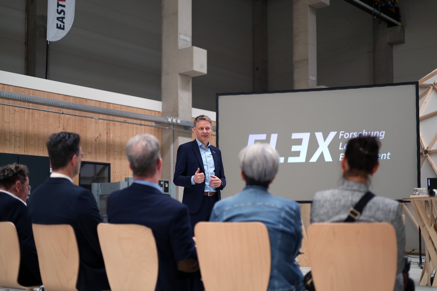 Präsentation ein Mann hält einen Vortrag in einer Holzhalle