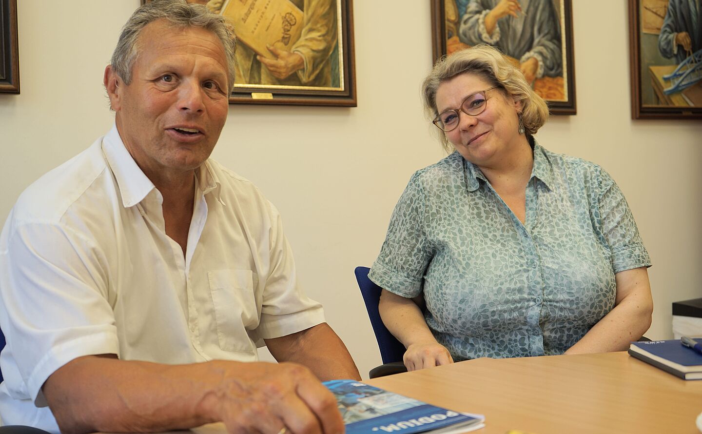 Honorarprofessoren Thomas Schmertosch und Birgit Reißig sitzen an einem Tisch im Senatsvorraum der Hochschule