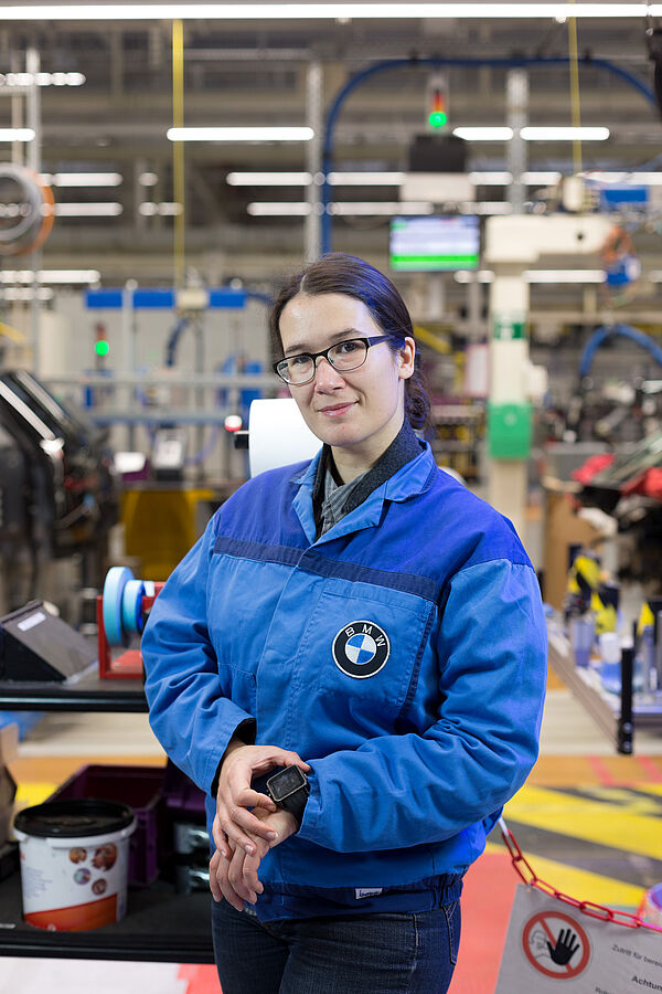 Dr. Nele Drünert steht im Leipziger BMW-Werk und zeigt ihre Smartwatch