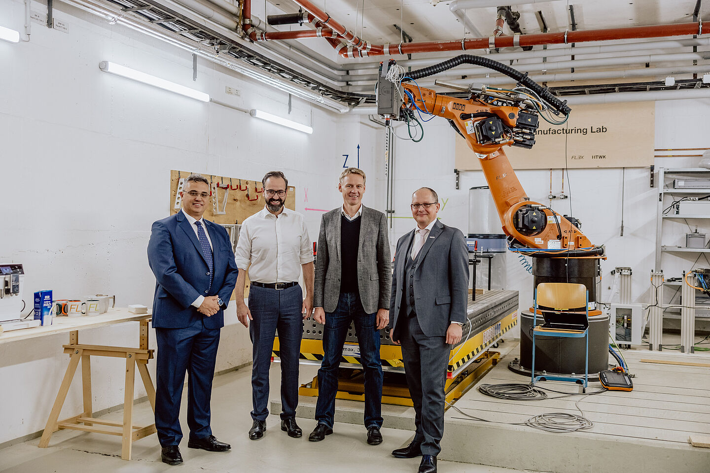 Vor einem Roboter stehen vier Männer: Prof. Faouzi Derbel, HTWK-Prorektor für Forschung und Nachhaltigkeit, Wissenschaftsminister Sebastian Gemkow, Prof. Alexander Stahr, Leiter der Forschungsgruppe FLEX sowie Prof. Mark Mietzner, Rektor der HTWK Leipzig