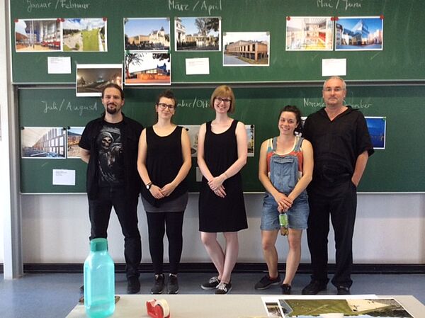 Gruppenfoto von fünf Menschen vor einer Tafel