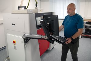 ein Mann schaut aufs Bedienfeld einen Druckers