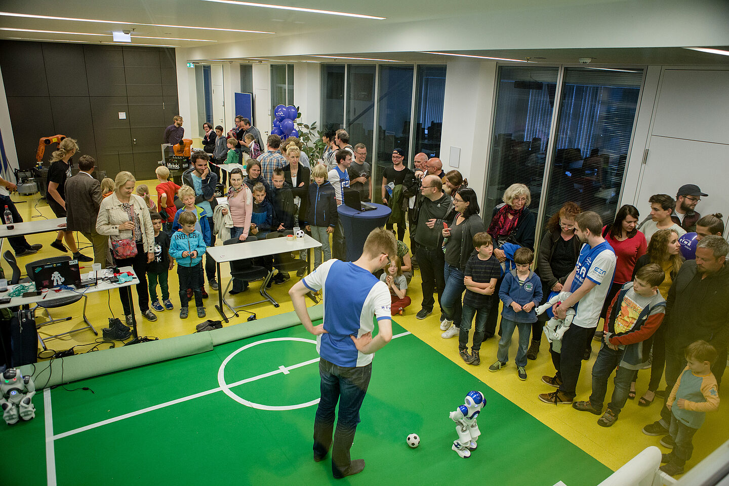 Ein Fußballroboter mit seinem menschlichen „Trainer“ auf dem Kunstrasen.