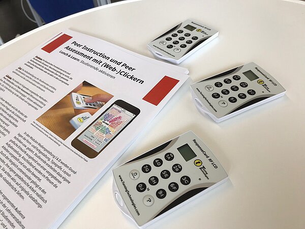 Lunch & Learn 2019 an der HTWK Leipzig (Foto: Sharon Geißler) Drei digitale Abstimmungsgeräte (optisch ähnlich Taschenrechnern) und Benutzungshinweise auf einem Tisch.